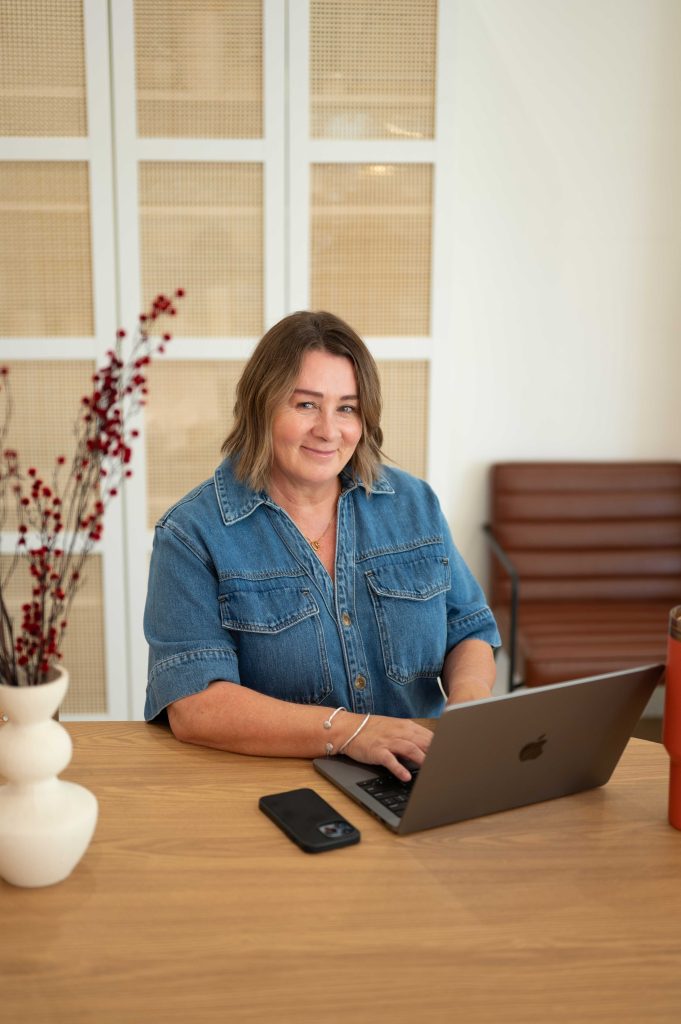 Woman in a denim shirt working on a laptop during a brand content session in an Adelaide Hills studio