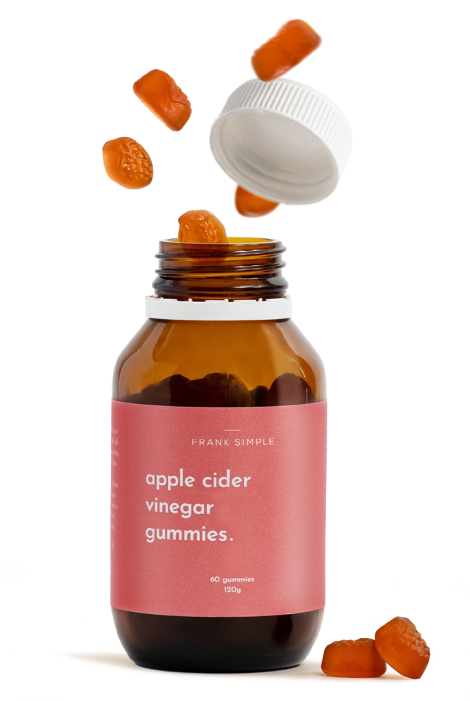 Amber supplement bottle with capsules falling above it in a minimal studio product photography setup.