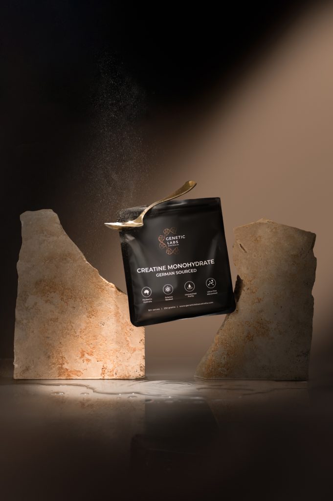 Genetic Labs creatine monohydrate powder with spoon and product dust in dramatic studio lighting