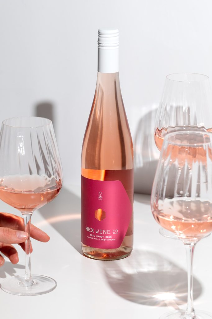 Hex Wine Co rose wine bottle with poured glasses on clean studio background