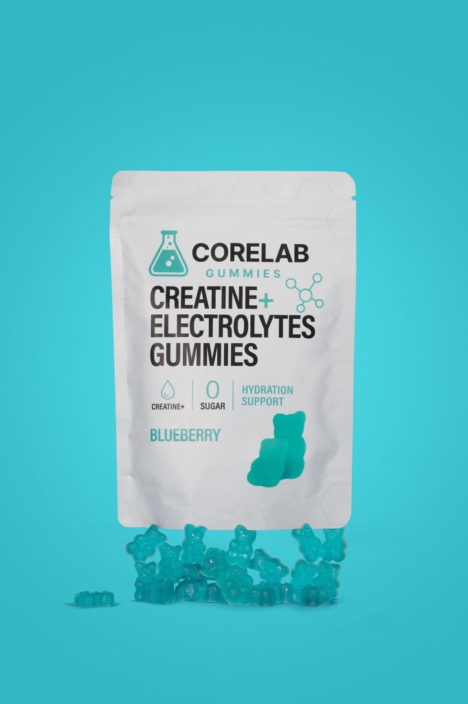 Vertical shot of the Corelab blueberry creatine and electrolyte gummies pouch on a blue background with gummy bears scattered below.
