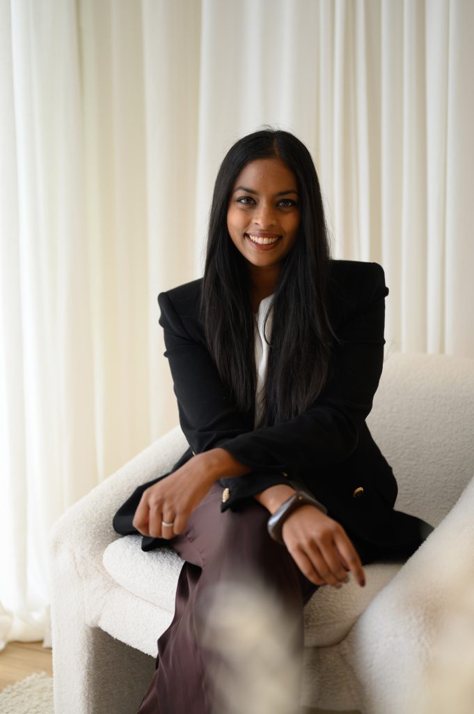 Professional headshot of a woman in a black blazer seated in a natural-light Adelaide studio