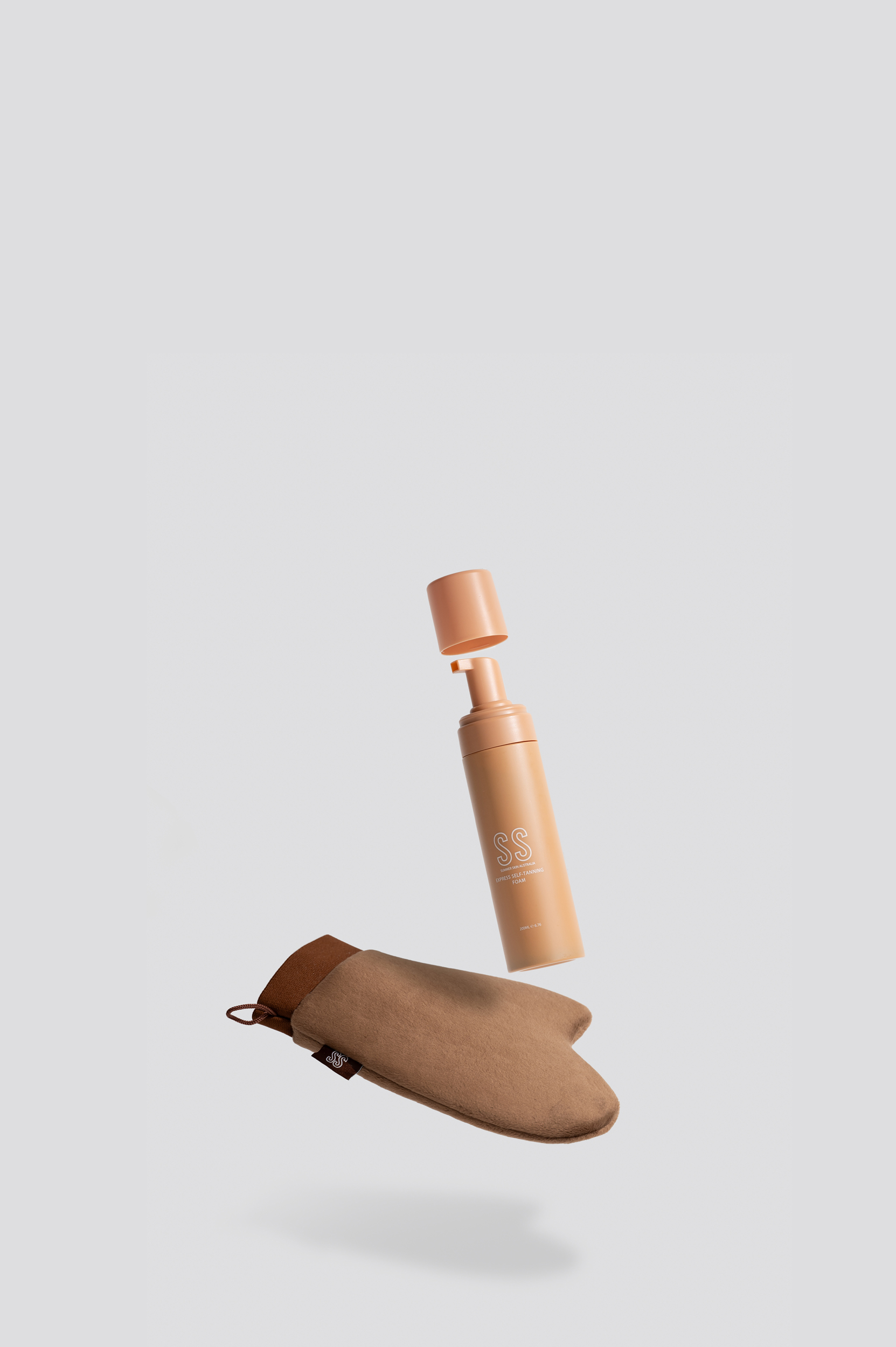 Summer Skin Express Self-Tanning Foam bottle and tanning mitt floating on a grey background
