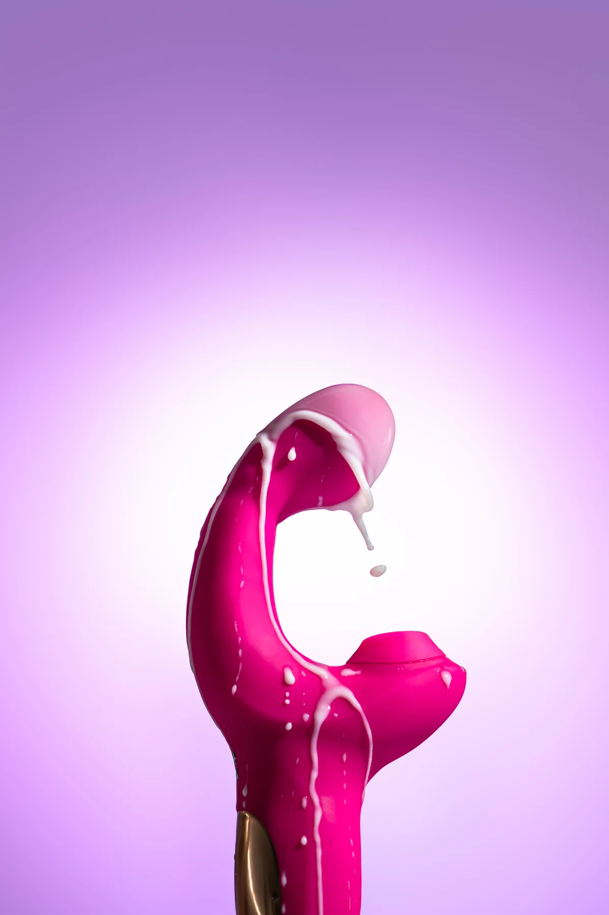 Pink silicone personal massager with a white liquid pour on a purple gradient background