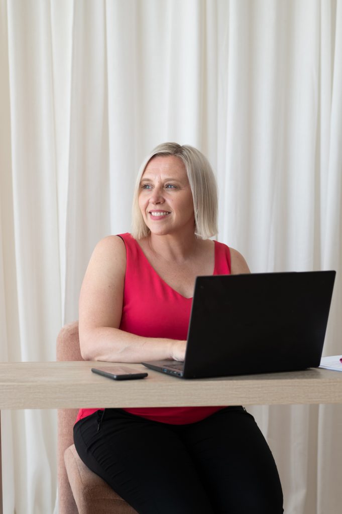Business owner Kristie working on a laptop at a desk in a bright studio during a brand photography session.