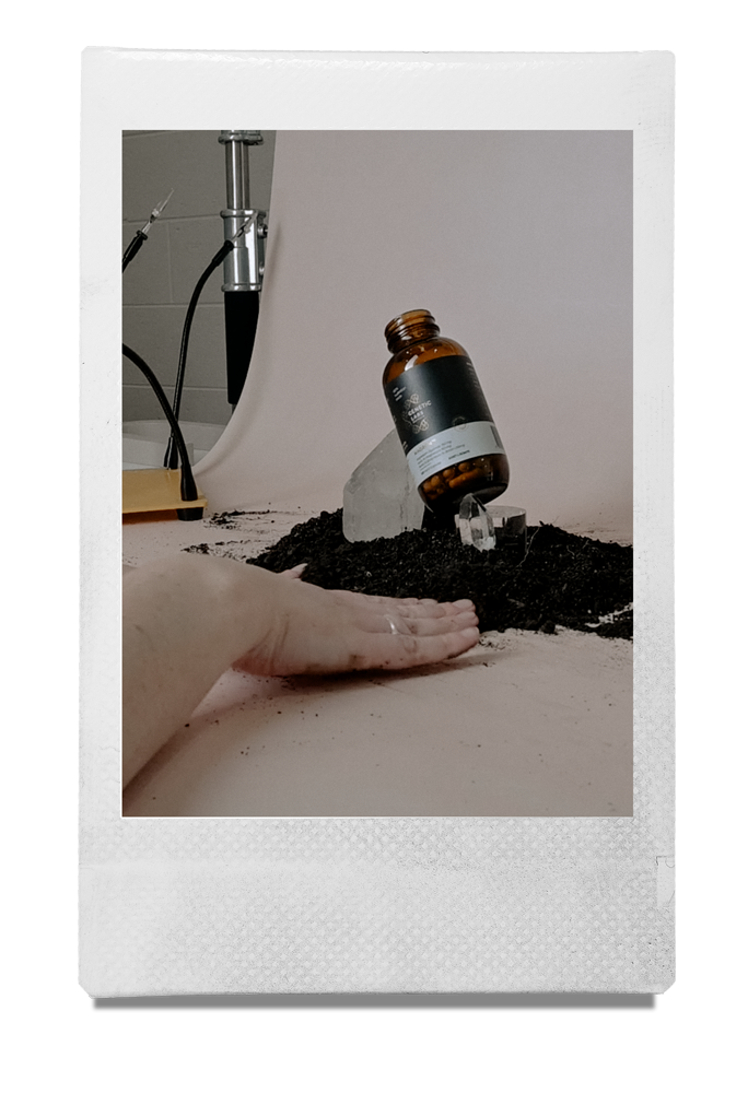 Behind-the-scenes product photography set with an amber bottle, soil and crystals in the Mindful Creatives studio.
