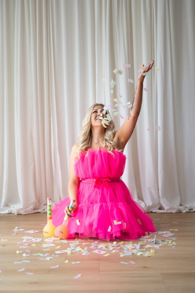 Woman in a bright pink dress throwing confetti during a Rapid Session at Mindful Creatives Studio