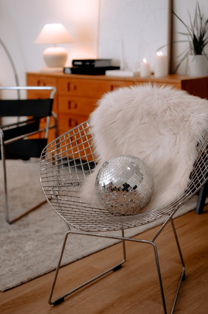 Chrome wire chair styled with a white sheepskin and silver disco ball inside the studio